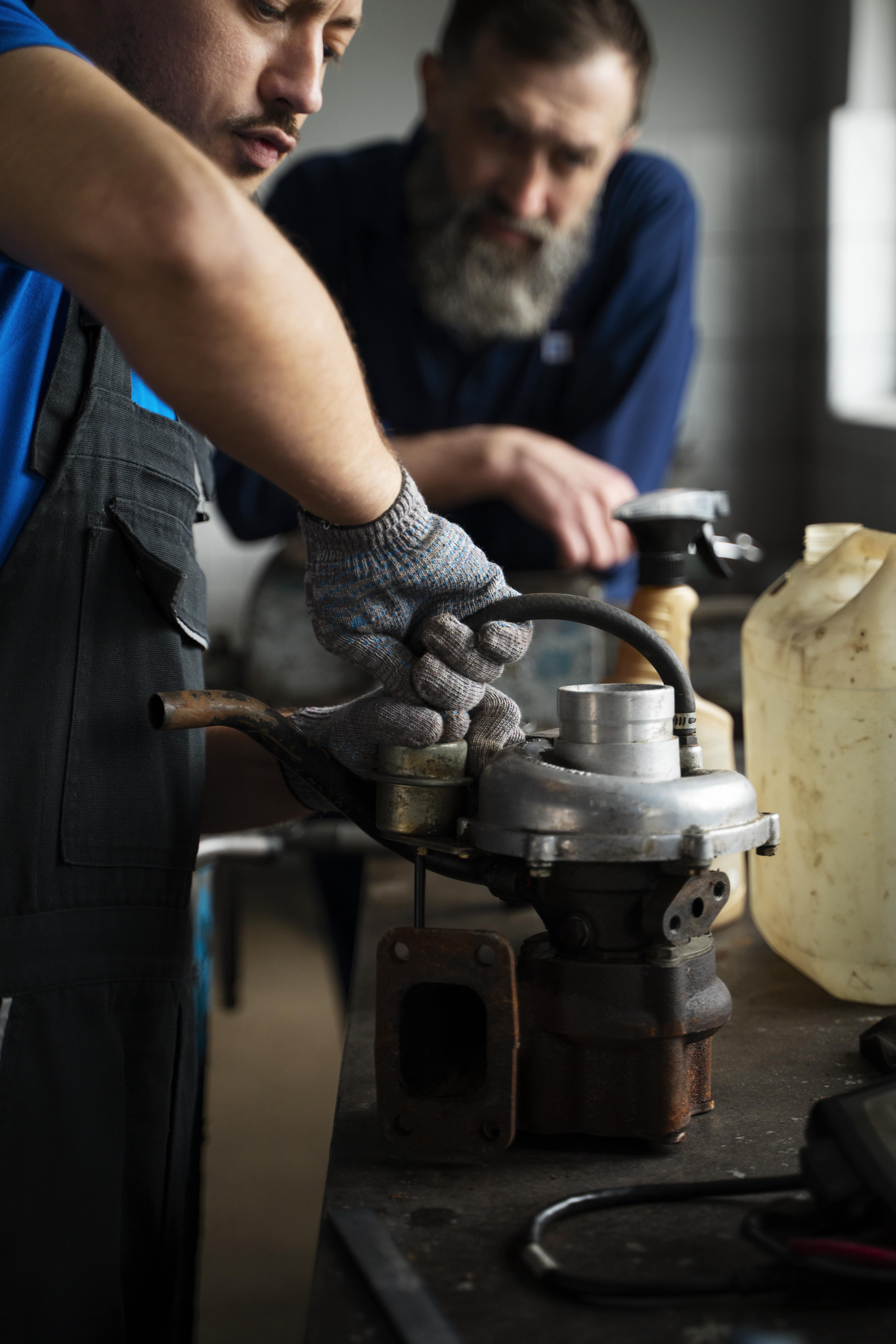 male-mechanics-working-car-shop-together-min
